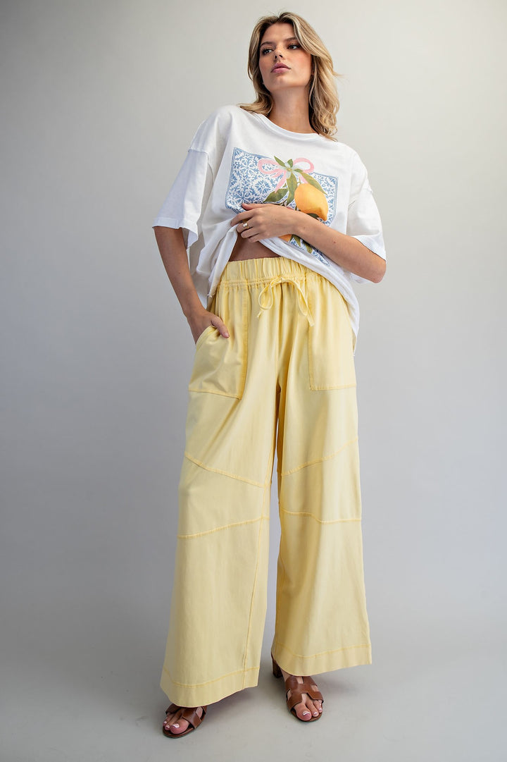 Woman wearing yellow sweatpants and graphic tee on plain grey background
