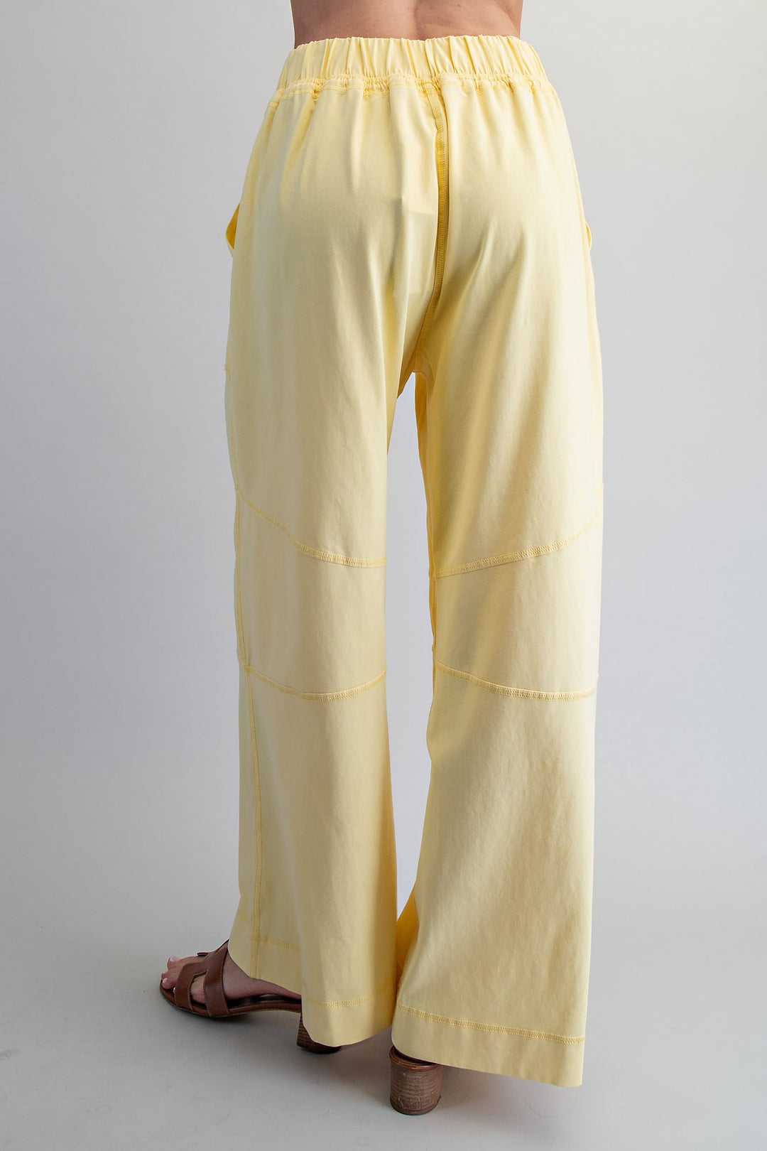 Yellow pants worn by a person on a plain background