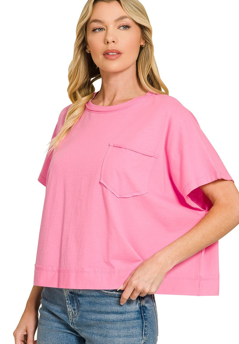 A woman wearing a bright pink short-sleeve crewneck t-shirt with a chest pocket, paired with blue jeans, against a plain white background.