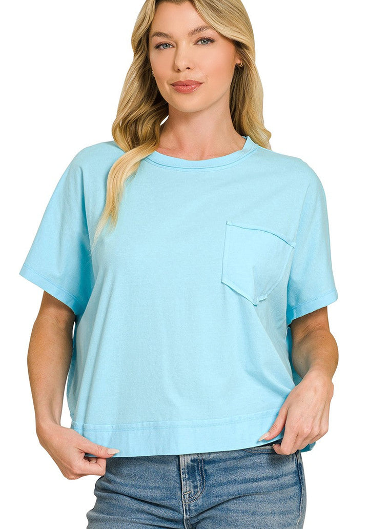A woman wearing a light sky blue short-sleeve crewneck t-shirt with a chest pocket, paired with blue jeans, against a plain white background.