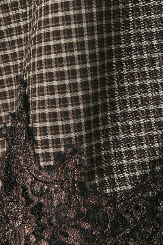 Close-up of a dark brown and beige plaid fabric with a black lace trim along the bottom edge.