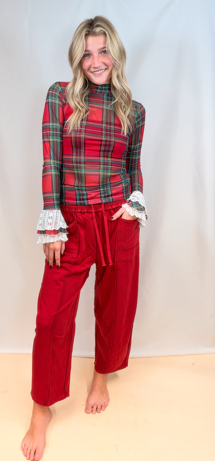 Woman wearing red tartan sheer top and red pants on plain background
