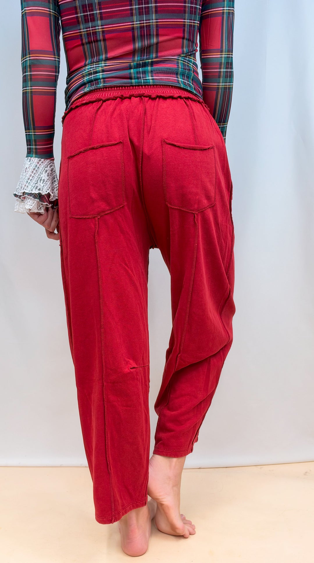 Woman shown from back view wearing red barrel style sweatpants on plain background