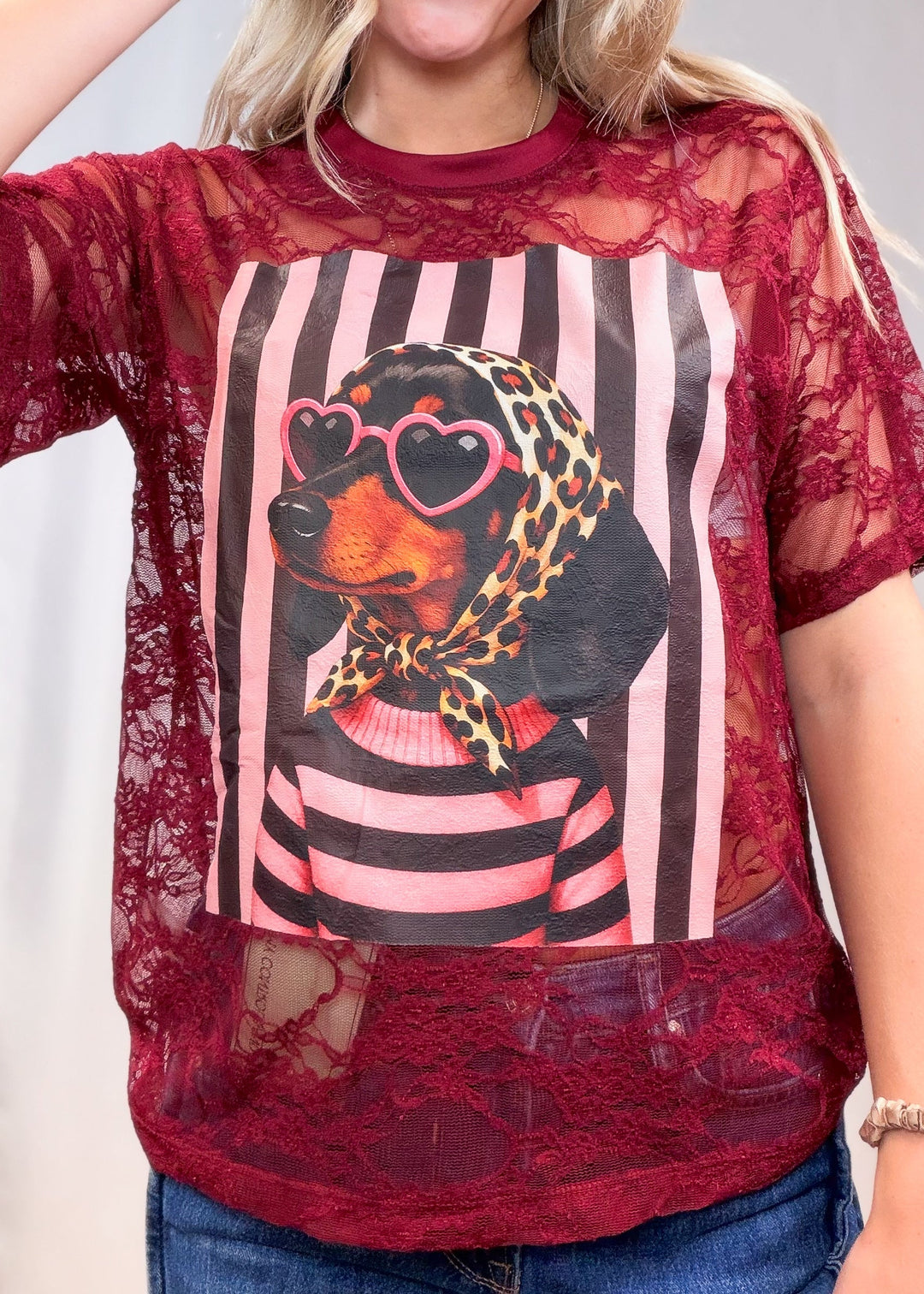 Woman wearing burgundy lace tee with doxie graphic on front on plain background