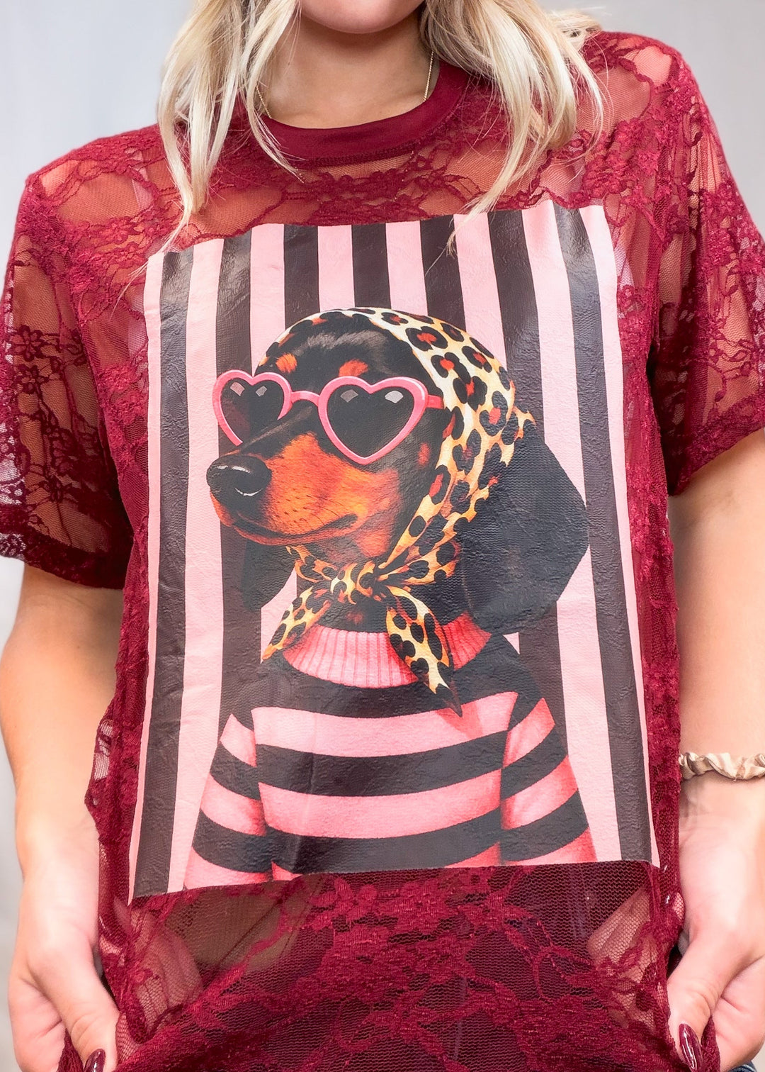 Woman wearing burgundy lace tee with doxie graphic on front on plain background