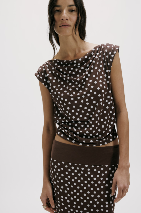 Woman wearing a brown polka dot top and skirt on a white background