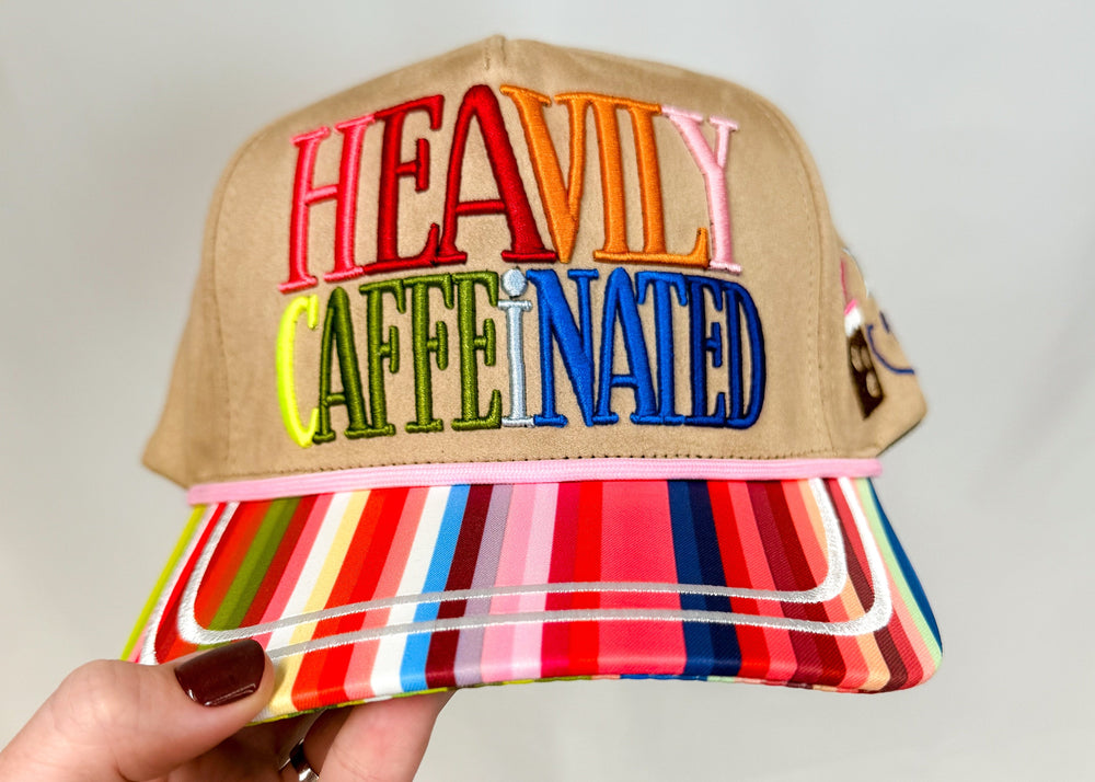Trucker hat with bright stripe bill and 'heavily caffeinated' embroidered on front on white background