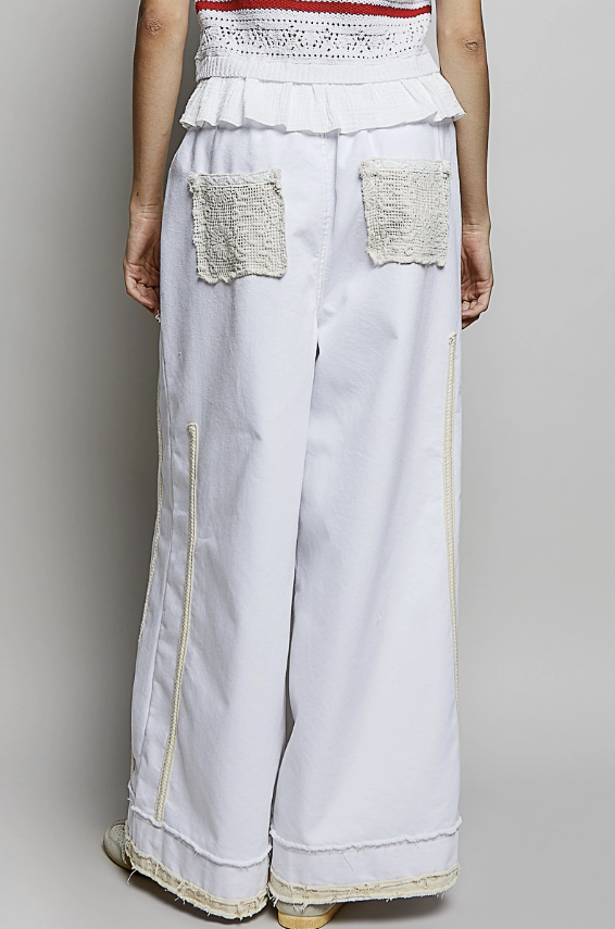 Woman wearing white and lace pant on plain background
