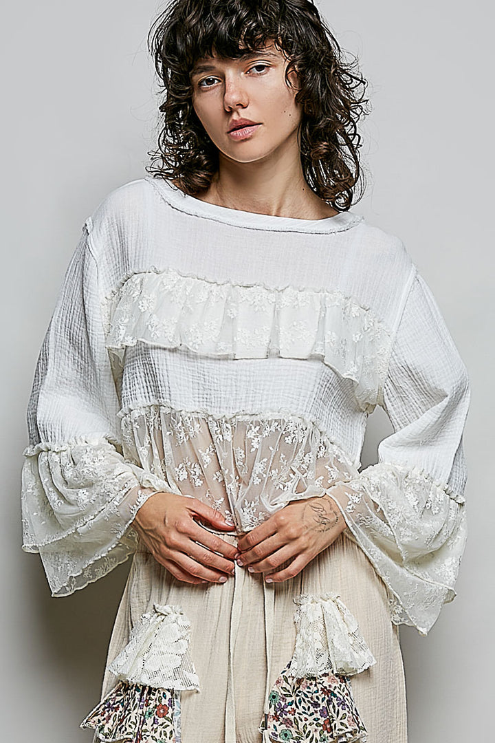Woman wearing a white and beige dress with floral details against a plain background