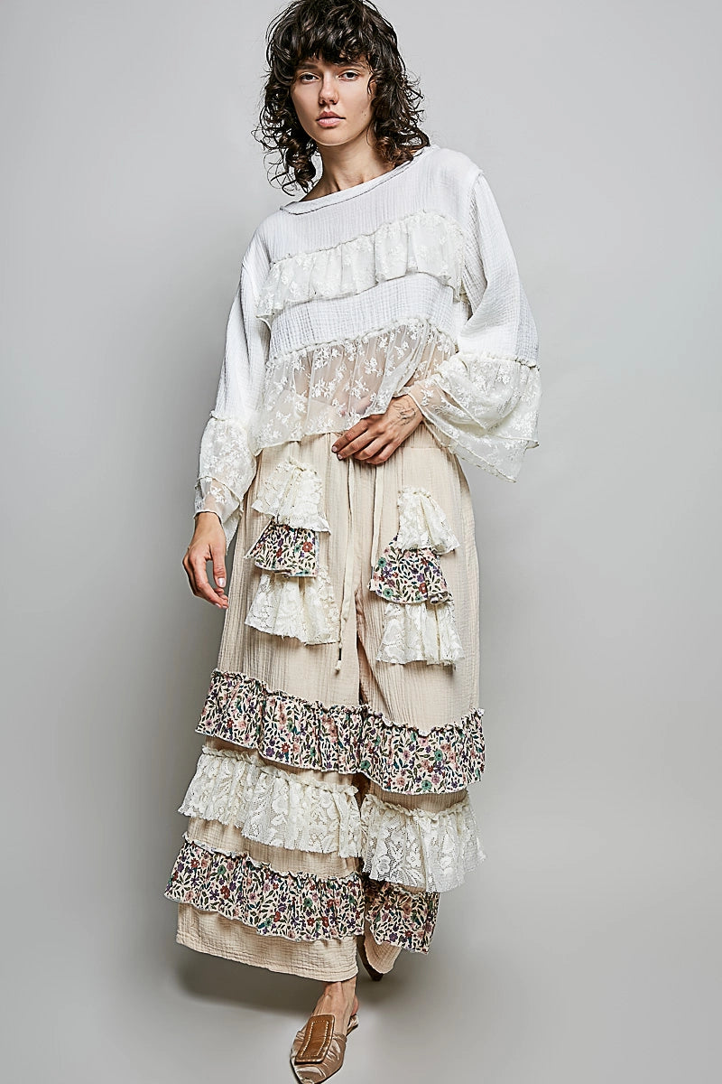 Woman wearing lace and gauze top with ruffle pants on gray background