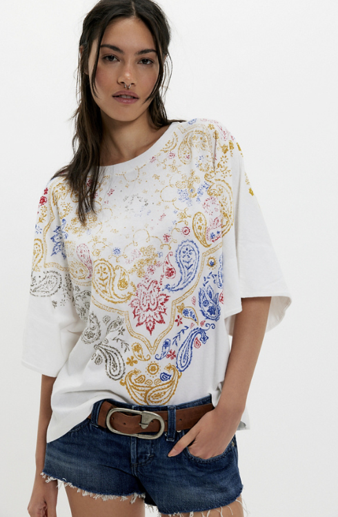 Woman wearing white tee with bandana print on plain background