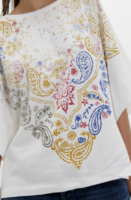 Woman wearing white tee with bandana print on plain background