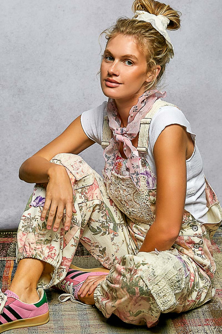 Woman sitting on a textured surface wearing a floral outfit with a gray background