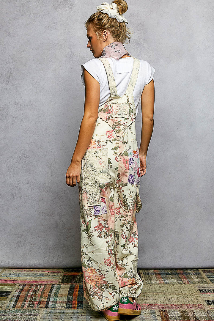 Woman wearing floral overalls against a gray wall.