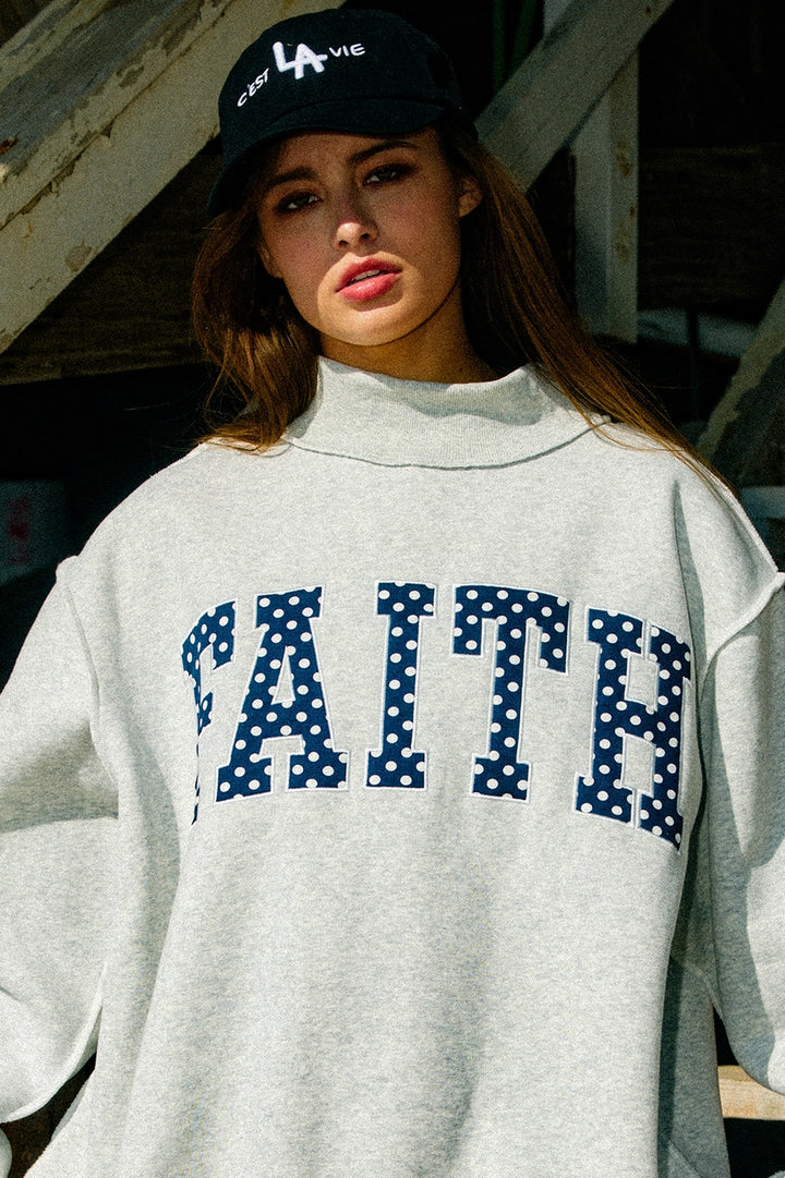 Woman wearing grey sweatshirt with &