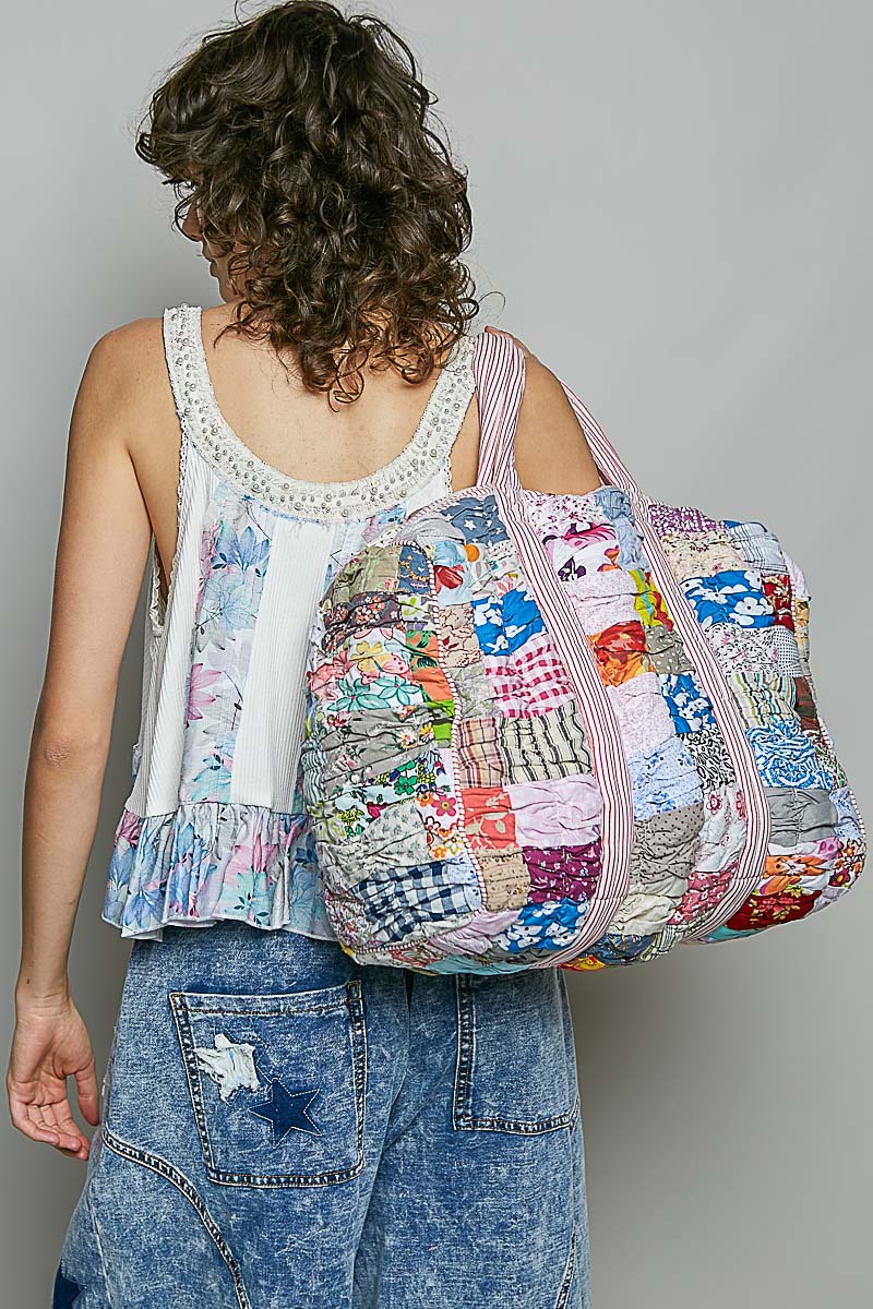 Woman holding quilted bag on plain background
