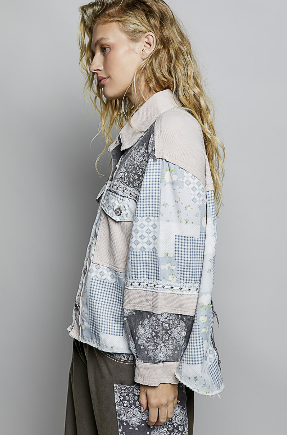 Person wearing a patchwork jacket with a neutral background