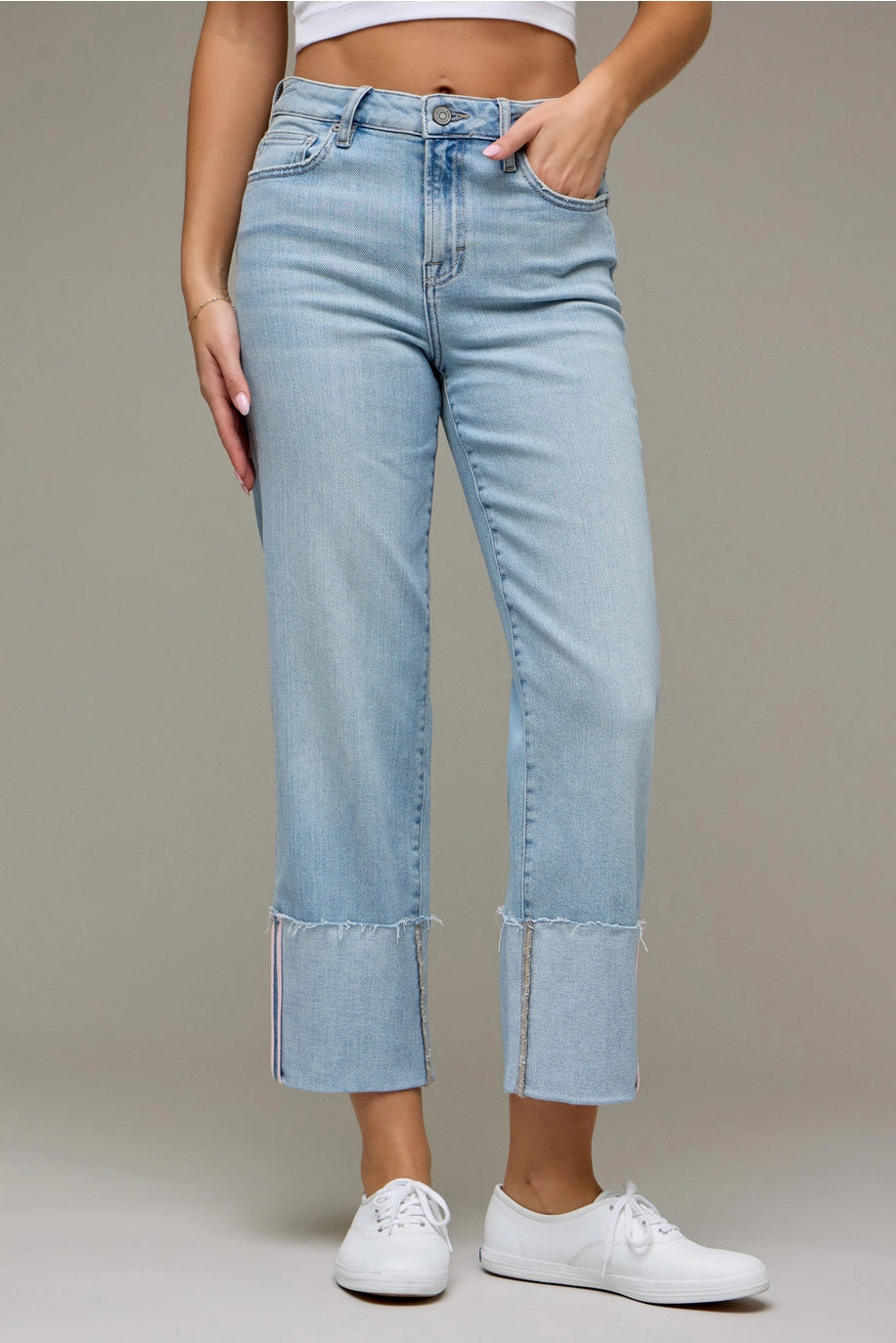 Woman wearing light wash denim pants on plain background