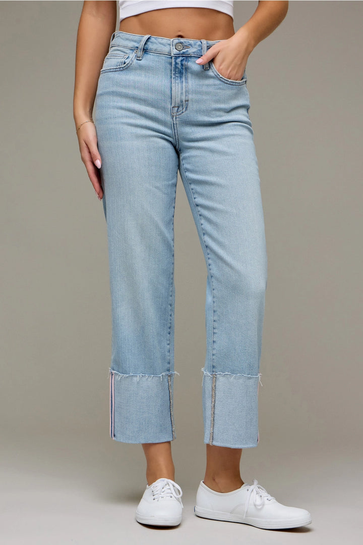 Woman wearing light wash denim pants on plain background