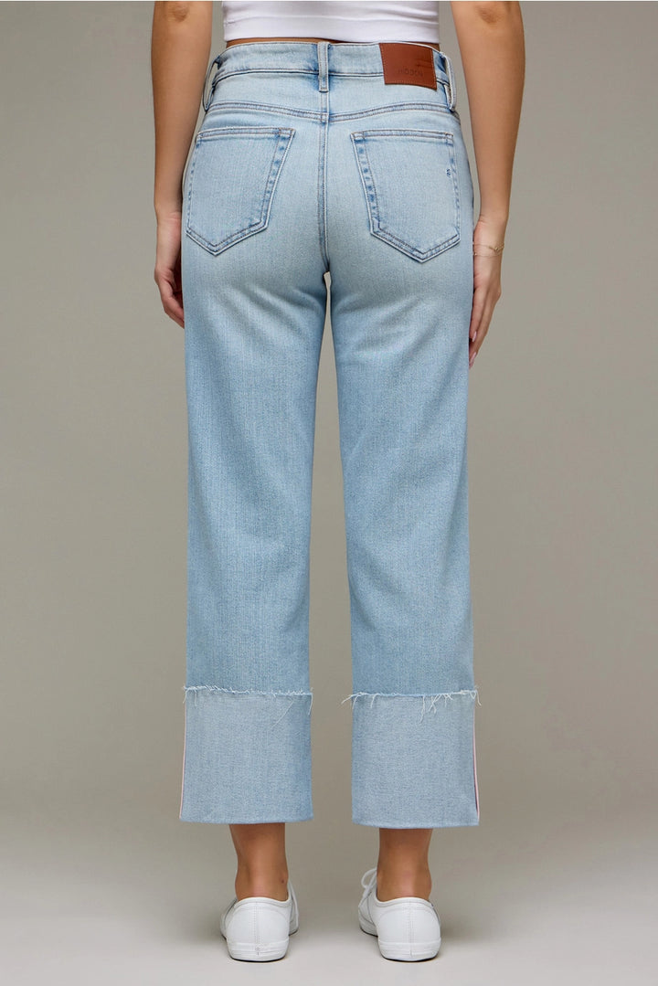 Back of woman wearing light wash denim pants on plain background