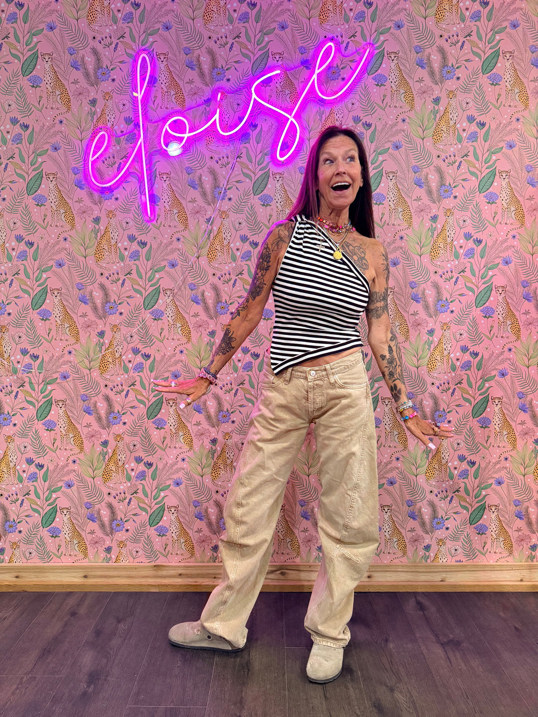 Woman wearing blue and white stripe top and beige pants on floral background
