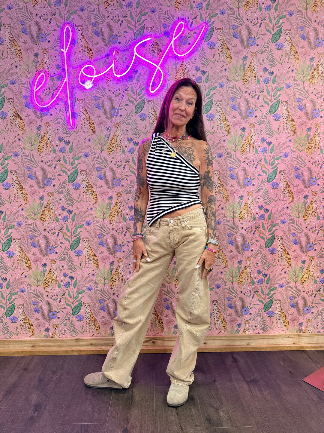 Woman wearing blue and white stripe top and beige pants on floral background
