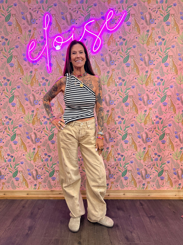 Woman wearing blue and white stripe top and beige pants on floral background