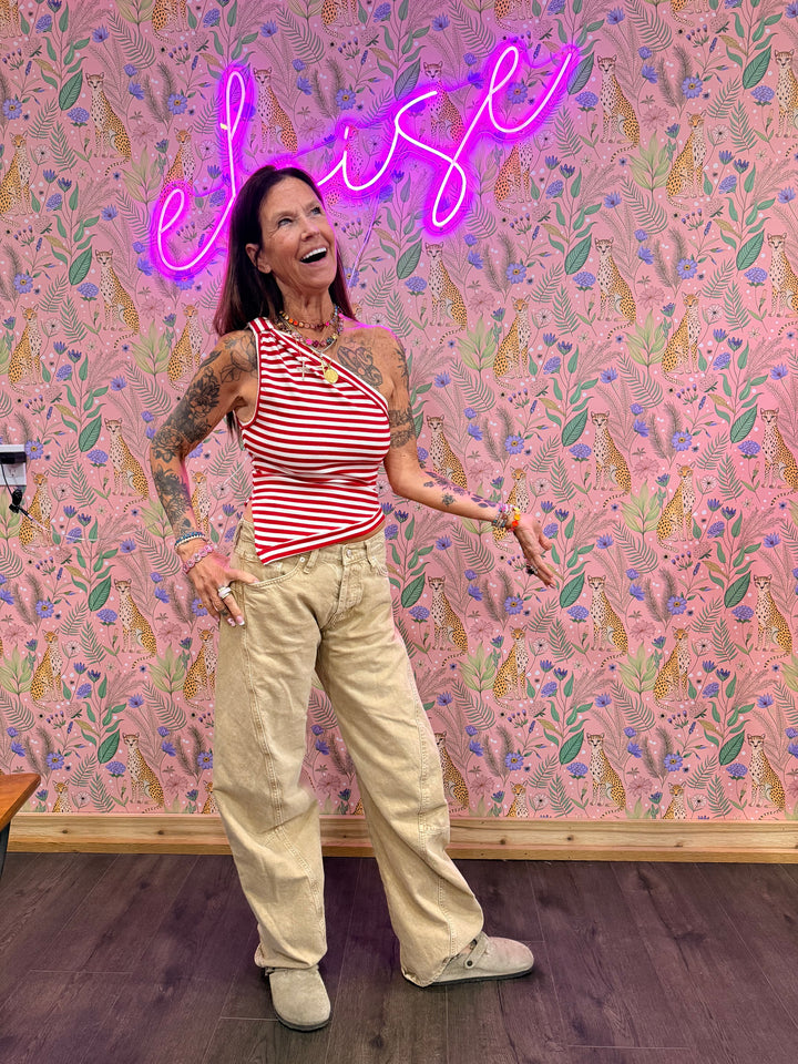 Woman wearing red and white stripe top and beige pants on floral background