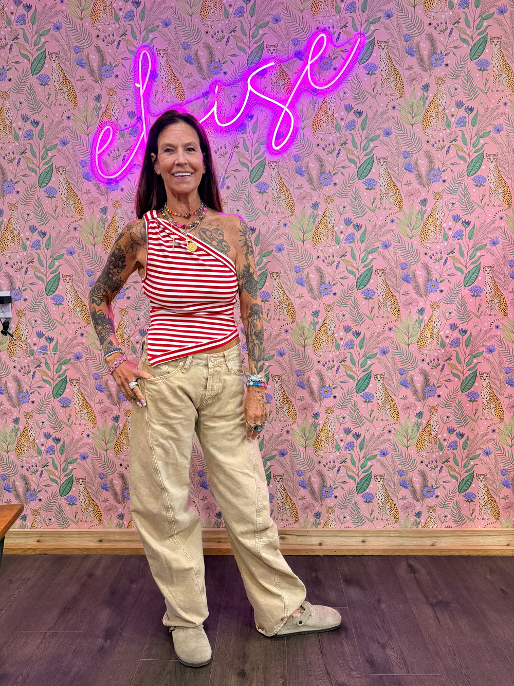 Woman wearing red and white stripe top and beige pants on floral background
