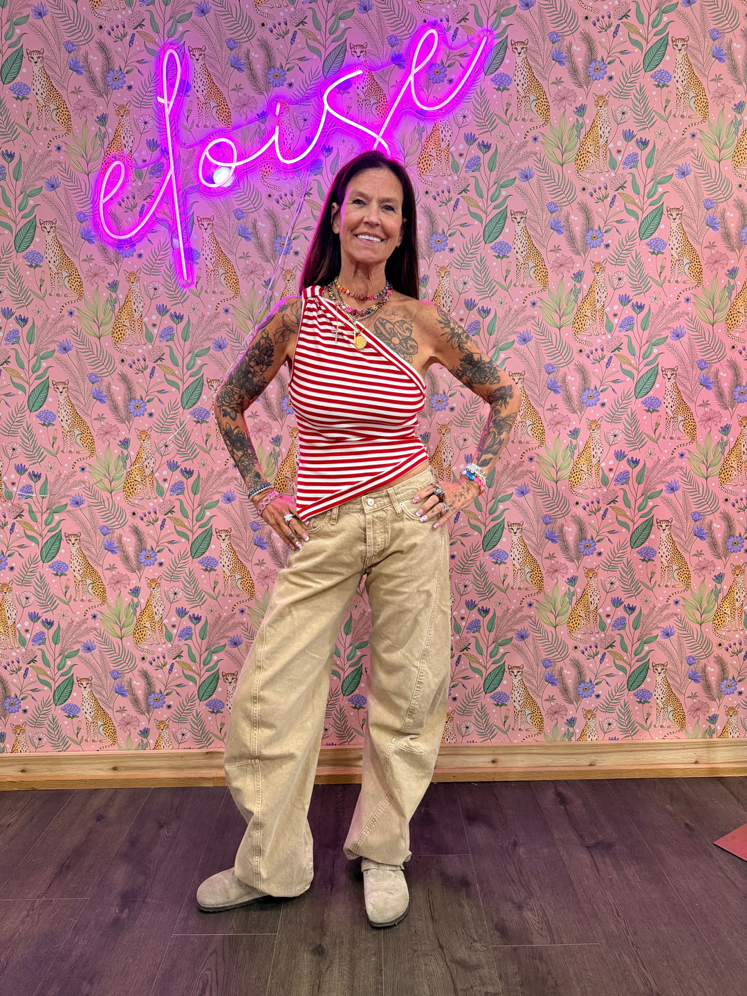 Woman wearing red and white stripe top and beige pants on floral background