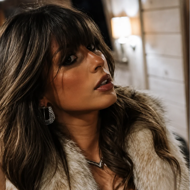 Woman wearing mini silver buckle earrings with fur jacket