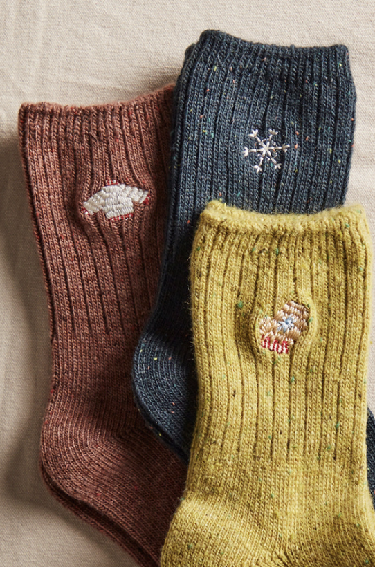 Three pair of knit socks with holiday embroidery on plain background