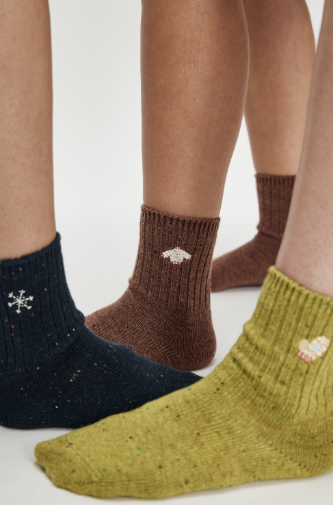 Three different knit socks with holiday embroidery on white background