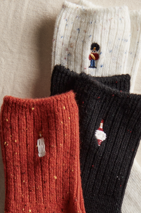 Three knit socks with holiday embroidery on plain background
