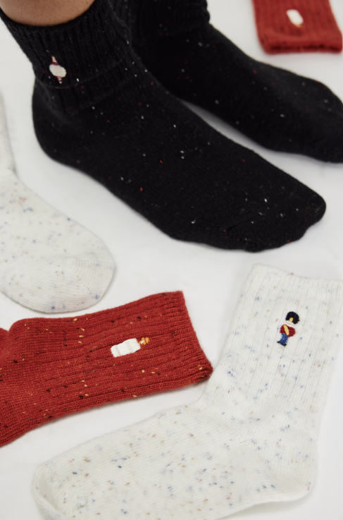 Three knit socks with holiday embroidery on plain background