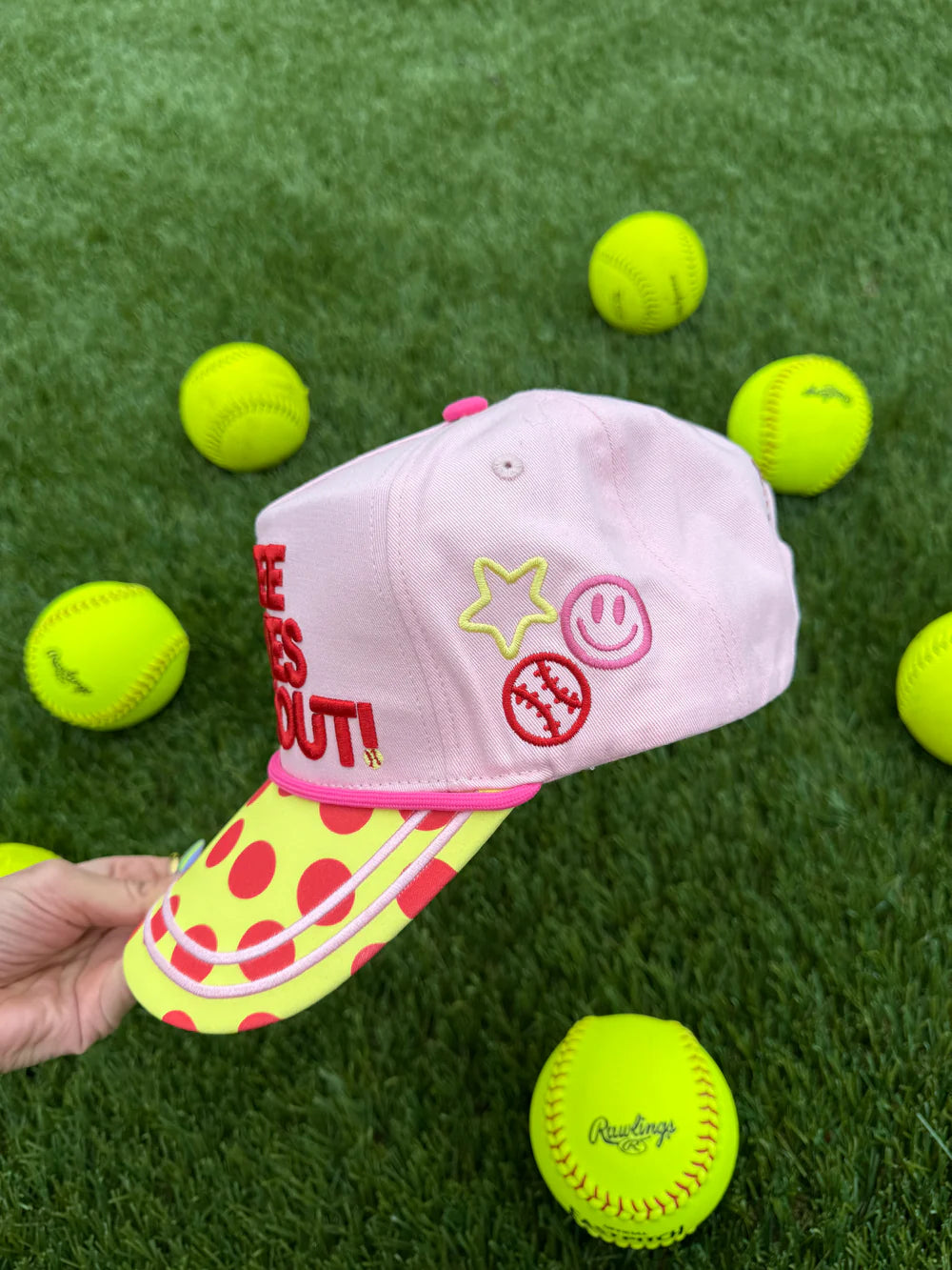 Pink cap with colorful design on a grass background with tennis balls