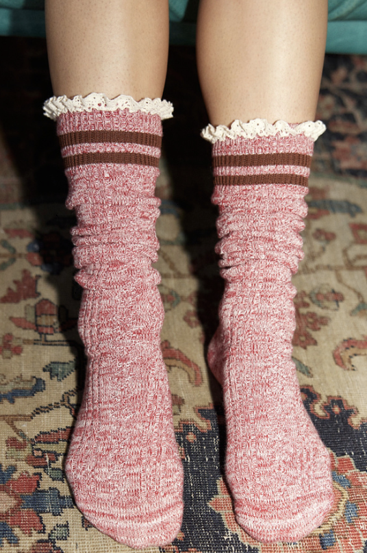 Pink socks with lace trim worn on a patterned carpet