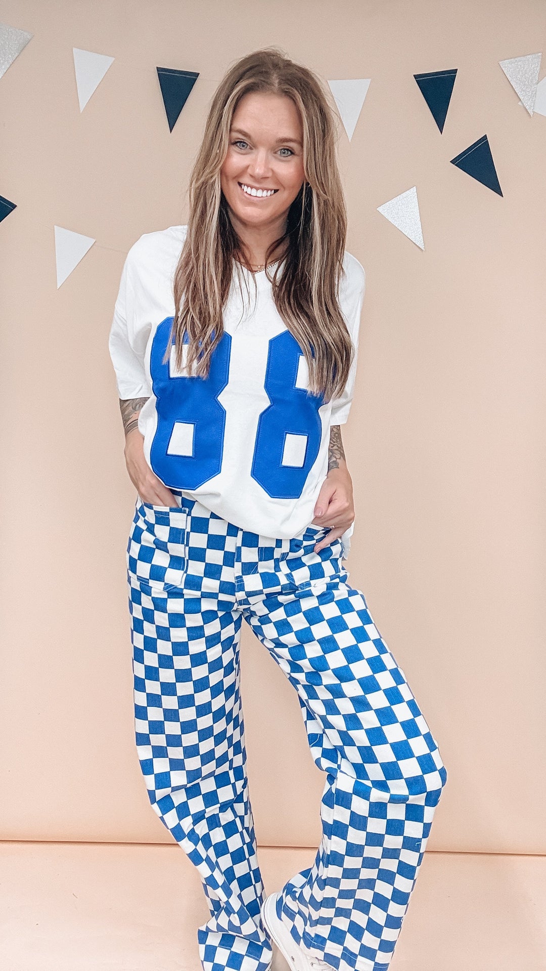 A woman modeling a white long-sleeve top with large blue &