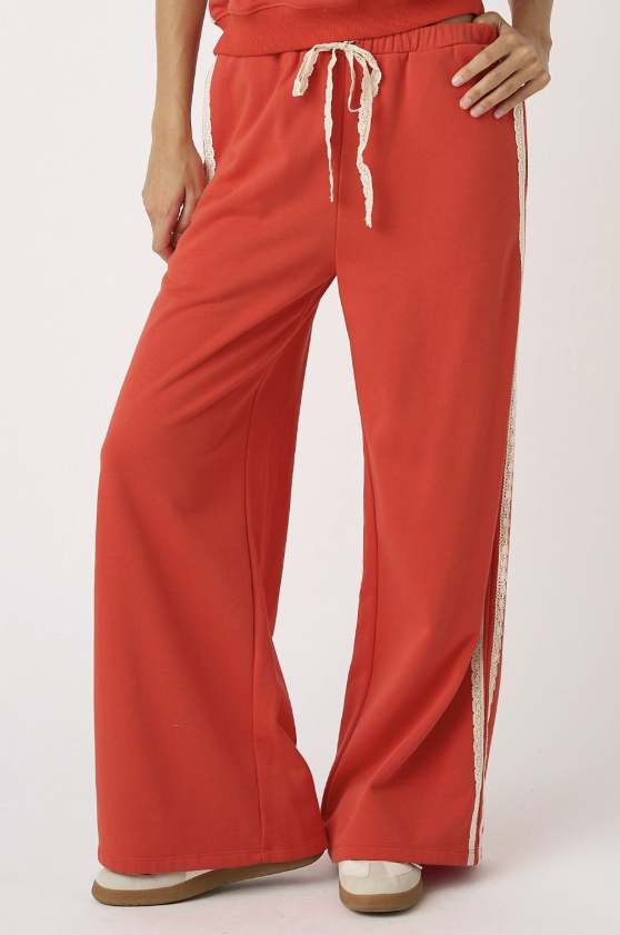 Red wide-leg pants with a white stripe on a white background
