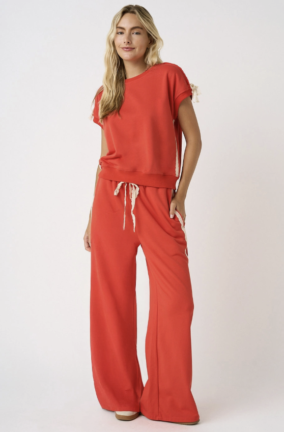 Woman wearing a red outfit with wide-leg pants on a white background