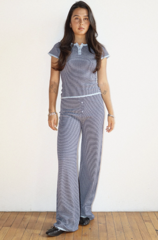 Woman wearing a patterned outfit standing against a plain background