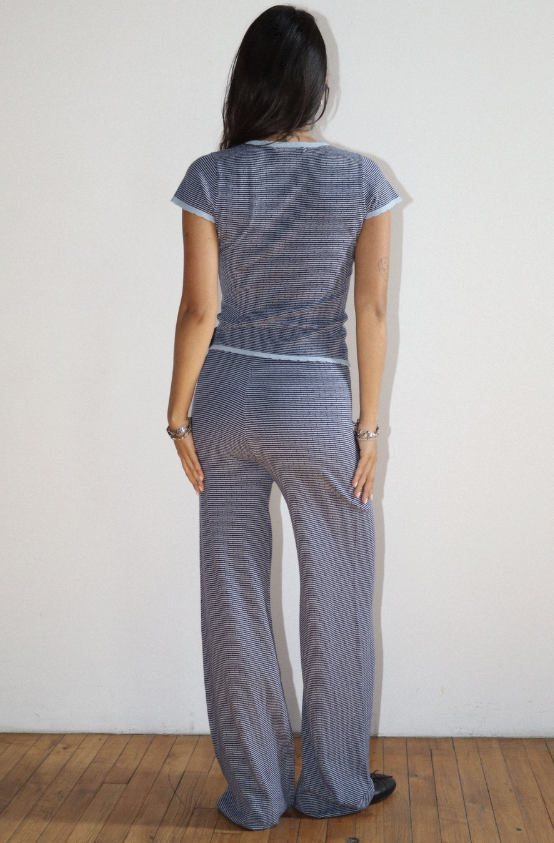 Woman wearing a gray patterned outfit against a white wall.