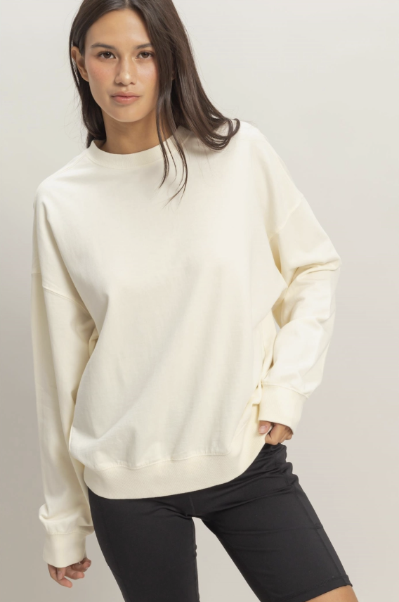 Woman wearing a cream-colored sweatshirt against a plain background