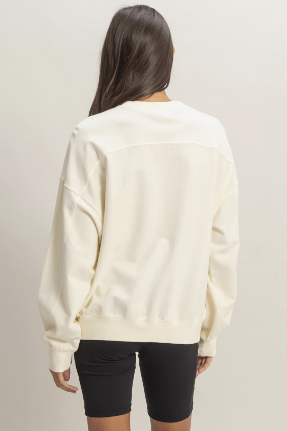 Person wearing a cream-colored sweatshirt against a plain background