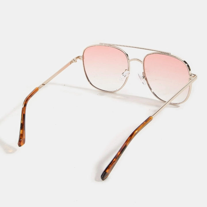 Sunglasses with pink gradient lenses and tortoiseshell arms on a white background