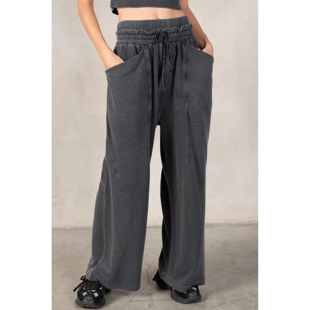 Person wearing gray wide-leg pants with a plain background