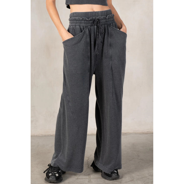 Person wearing gray wide-leg pants with a plain background