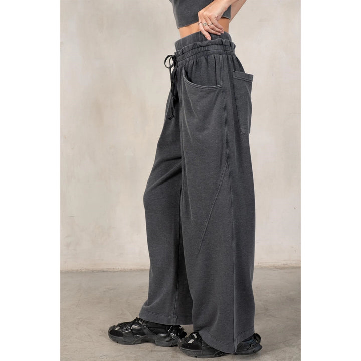 Person wearing dark gray wide-leg pants with a neutral background