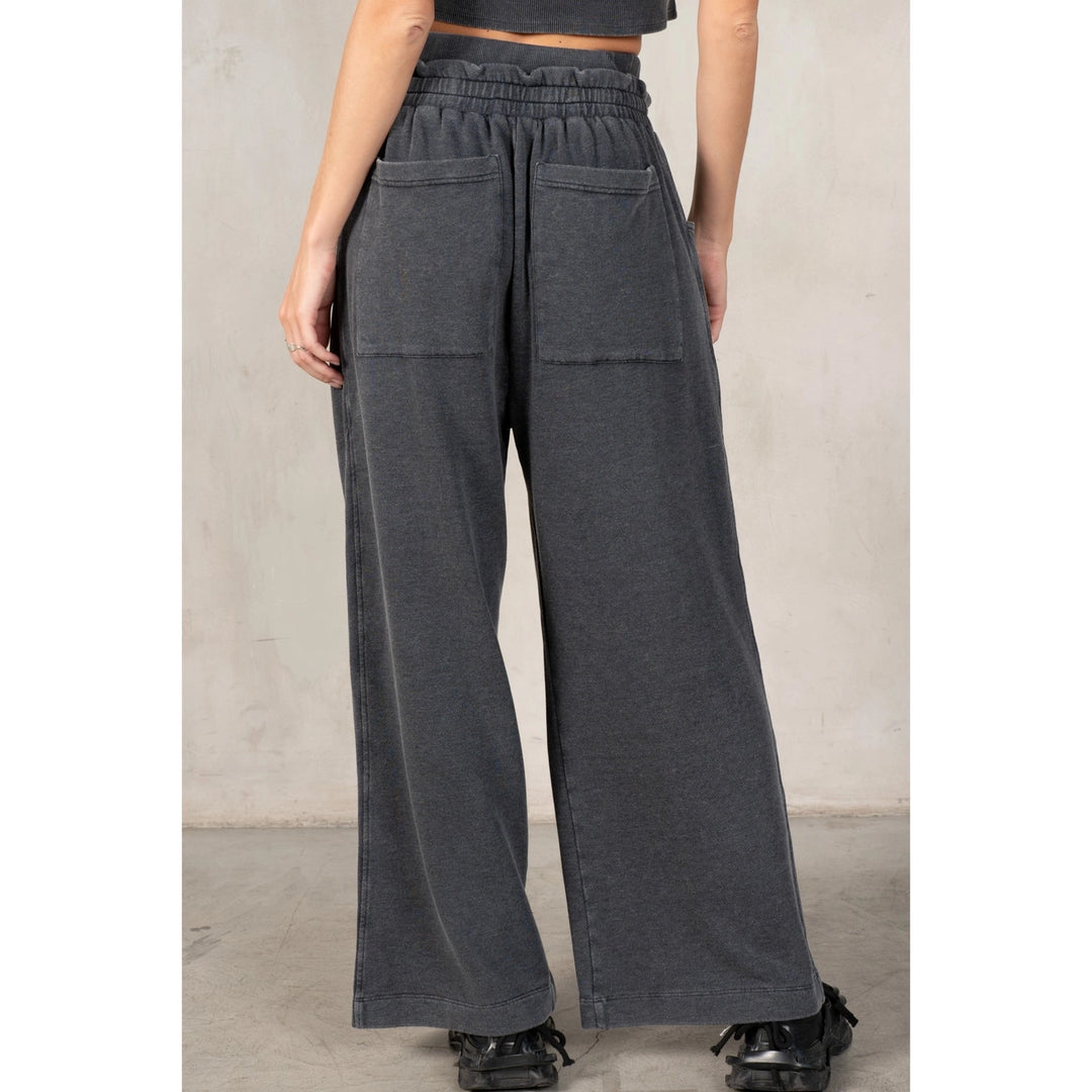 Person wearing dark gray wide-leg pants against a plain background