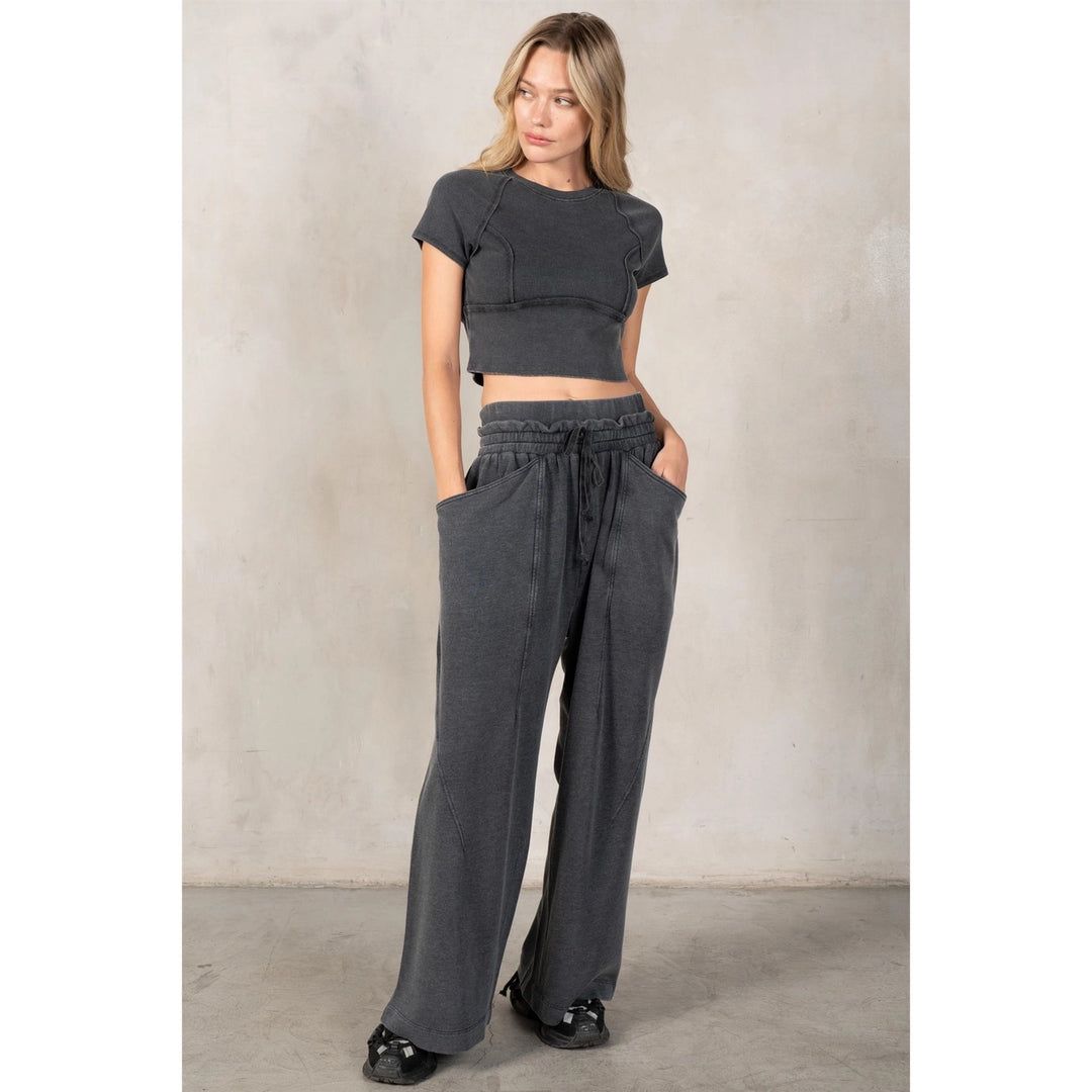 Woman wearing a gray crop top and wide-leg pants against a neutral background